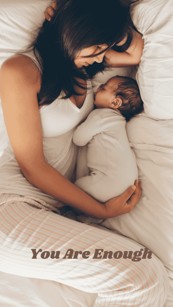 A mother in pajamas lies on the bed cradling her newborn baby 