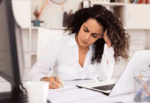 how to create a budget: woman sat at a desk, frustrated with her budget